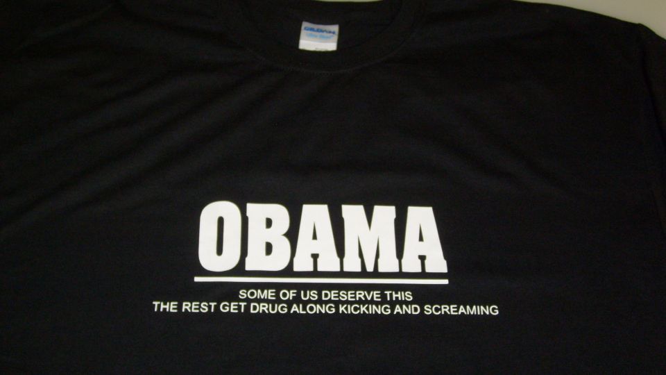 black t-shirt with "OBAMA" and "SOME OF US DESERVE THIS THE REST GET DRUG ALONG KICKING AND SCREAMING" text