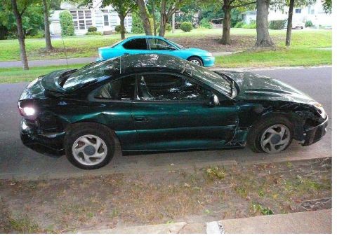1996 Dodge 1500 - A damaged green coupe sits on the side of the road next to a blue sedan.