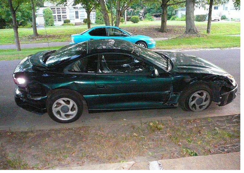 Green coupe with significant damage to the rear and front right side, flat front right tire