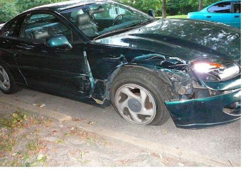 1996 Dodge 1500 - Green coupe with significant front-end damage and a flat tire. Another vehicle is parked behind it.