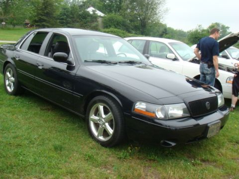 2004 Ford Crown Victoria - A black 2004 Ford Crown Victoria is parked on grass next to another vehicle.