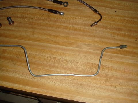 1992 Ford Bronco - Metal brake line and braided hoses are laid out on a wooden surface.