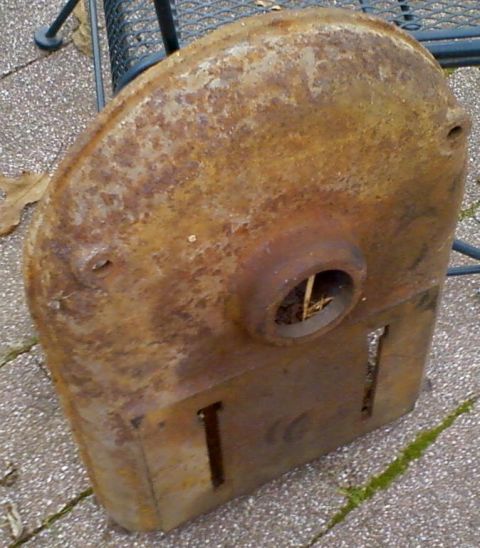 1995 Ford Bronco - This heavily rusted metal part sits on a paved surface outdoors.