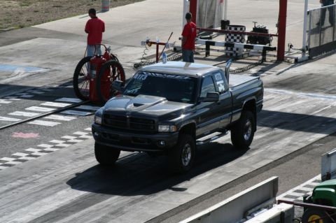 2002 Dodge 2500 - A modified pickup truck is on a drag strip, with two people and a fire suppression system visible in the background.