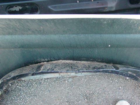 1979 Ford Bronco - Close-up view of a vehicle's wheel well and fender area, showing gravel and a damaged fender flare.
