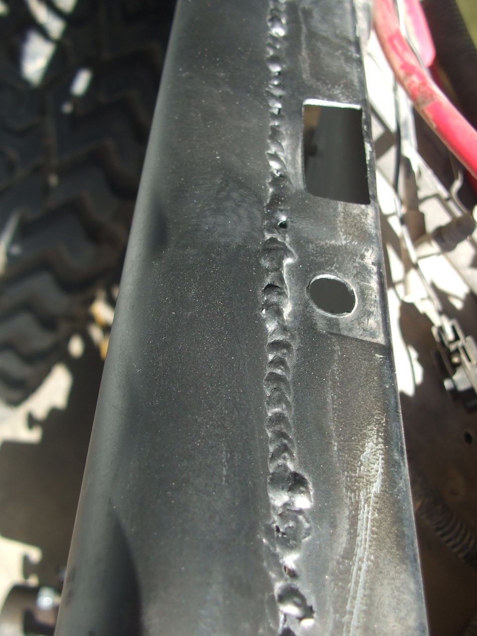 Close-up of welded metal frame with a square cutout and a circular hole