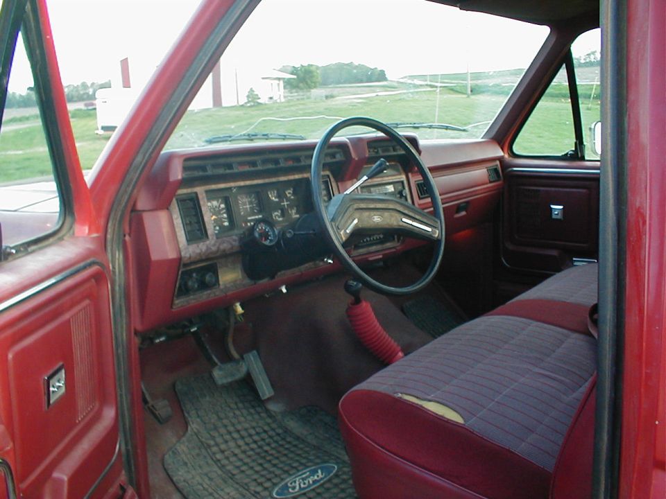 Red truck interior with column shift, bench seat and Ford floor mats