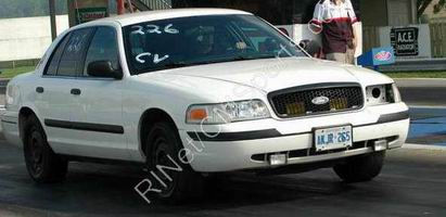2003 Ford Crown Victoria - A white 2003 Ford Crown Victoria is seen on a race track with a partial view of a person in the driver's seat.