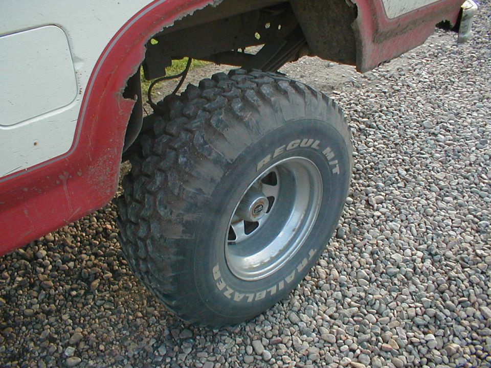 Off-road mud tire on aluminum wheel under a red truck fender