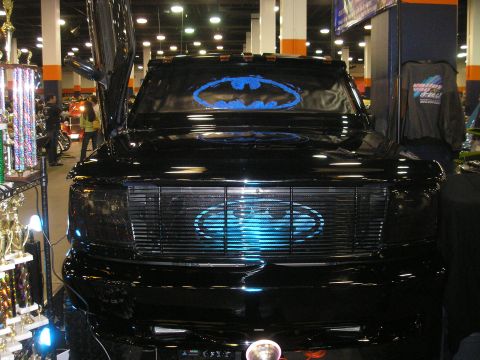 1995 Ford Bronco - A black truck modified with a bat symbol on the grille and windshield, with its butterfly doors open.