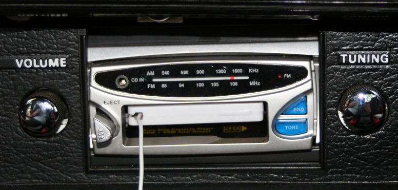 Retro AM/FM car radio with chrome volume and tuning knobs in black dash panel