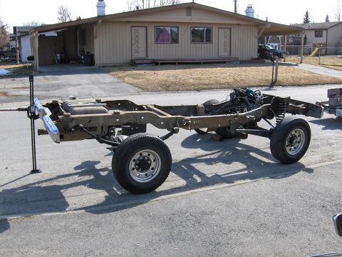 1990 Ford Bronco - Chassis of a truck, likely undergoing axle swap or repair, with engine and suspension components visible.