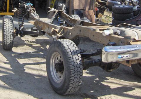 1990 Ford Bronco - The chassis of a 1990 Ford Bronco is shown from the side, with a rusty frame and chrome bumper.