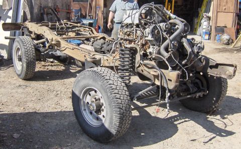 1990 Ford Bronco - The chassis and engine of a vehicle are shown, with the front suspension and tires prominent.