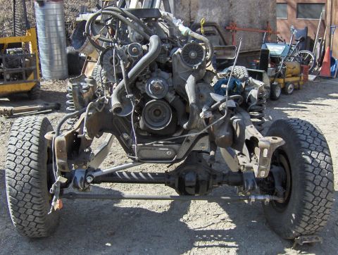 1990 Ford Bronco - Front end of a vehicle's chassis and engine assembly, with tires and suspension parts.