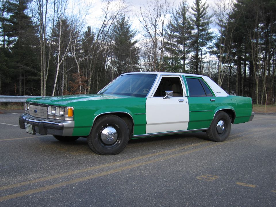 Front three-quarter of green and white Ford sedan parked on a road