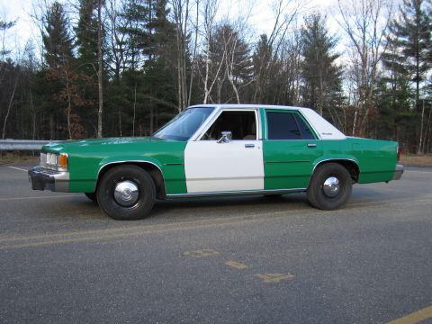 1991 Ford LTD Crown Victoria - Side profile of a green-and-white two-tone Ford sedan parked along a tree-lined road.