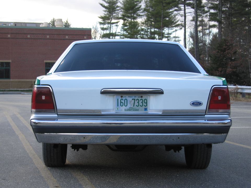 Rear of white Ford sedan, head-on, with NH plate 160-7339