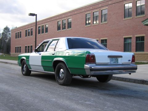 1991 Ford LTD Crown Victoria - Rear three-quarter view of a green-and-white full-size Ford sedan showing New Hampshire plate 1GO 7339, parked by a brick building.