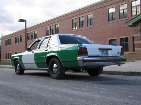 1991 Ford LTD Crown Victoria - Rear three-quarter view of a green-and-white full-size Ford sedan with a New Hampshire plate parked along a brick building.