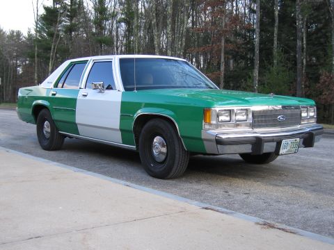 1991 Ford LTD Crown Victoria - Front passenger-side three-quarter view of a green-and-white Ford LTD Crown Victoria parked on pavement before bare trees.