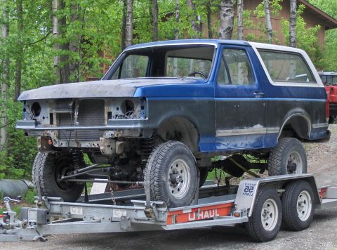 1990 Ford Bronco - This Ford Bronco, likely from the late 1980s, is missing its front grille and bumper, indicating it is undergoing repairs or modifications.