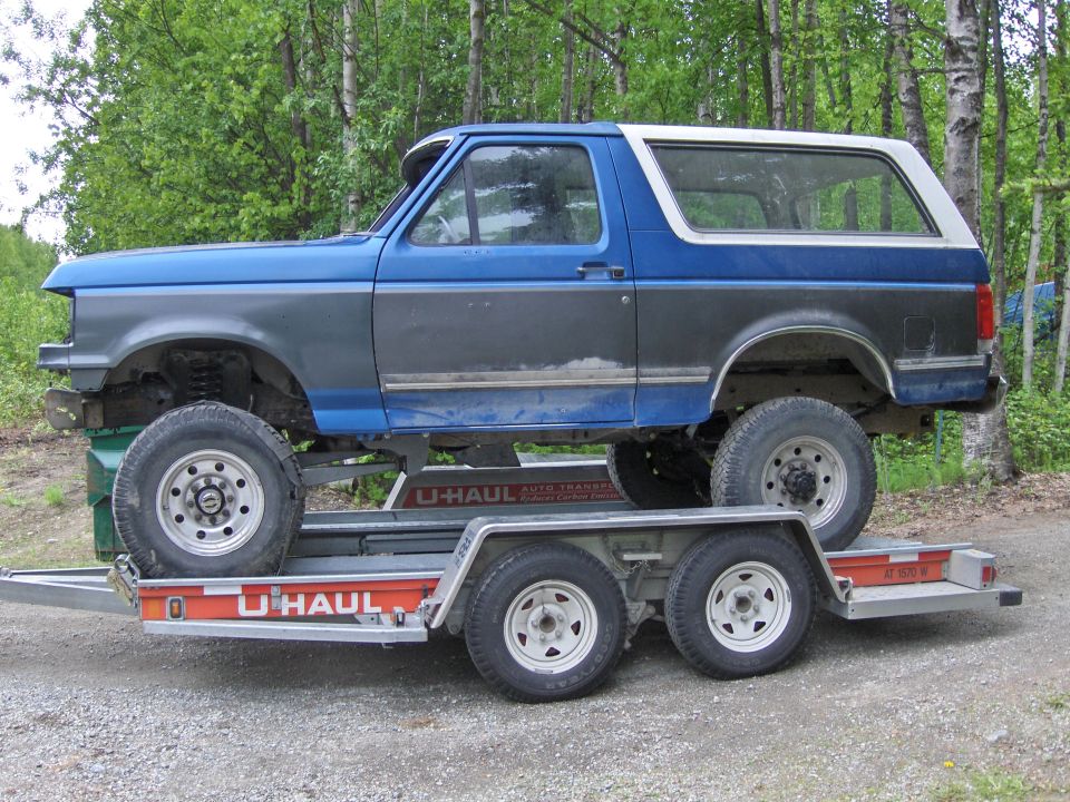 Blue and gray Ford Bronco SUV on an orange U-Haul auto transport trailer