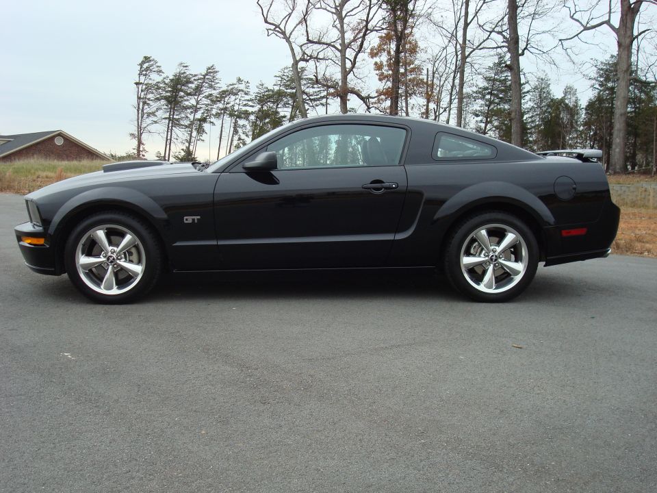 Black Mustang GT coupe side profile with polished five-spoke wheels and rear spoiler