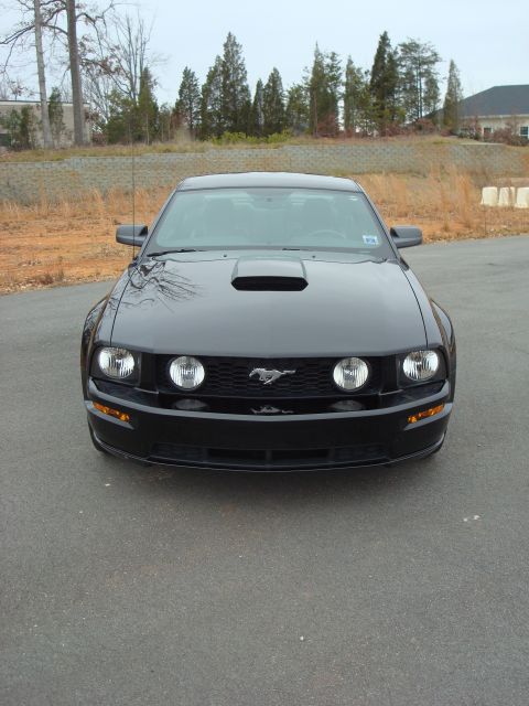 2007 Ford Mustang - A black Ford Mustang is parked outside on a cloudy day, showing its front grille and headlights.