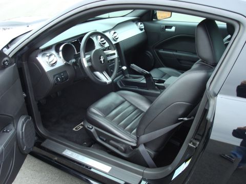 2007 Ford Mustang - The interior of a black Ford Mustang GT, viewed from the passenger side with the door open.