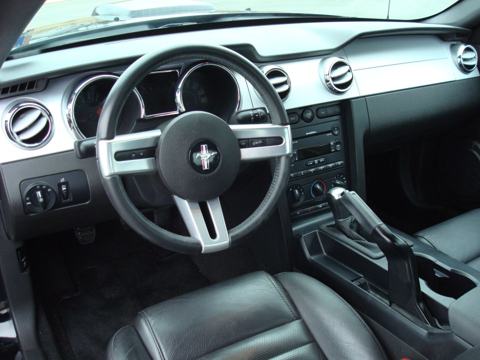 Black Mustang interior with pony-badged steering wheel, silver dash trim and shifter