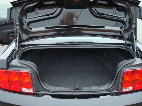 2007 Ford Mustang - The rear of a black car is shown with the trunk open, revealing the cargo area and taillights.