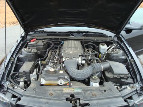 2007 Ford Mustang - The engine bay of a black car, viewed from above with the hood open.