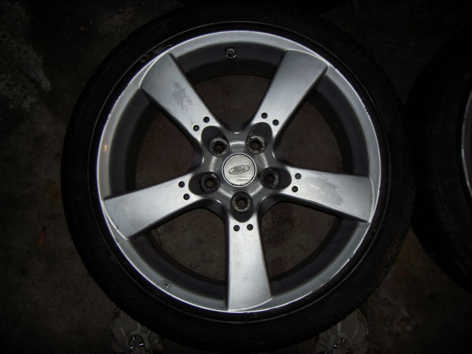 Silver five-spoke alloy wheel with a Ford logo center cap and tire