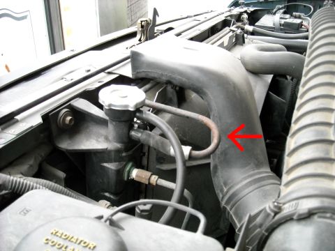 1994 Ford Bronco - Close-up view of the engine bay of a 1994 Ford Bronco, highlighting various components and a red arrow pointing to a metal hose.