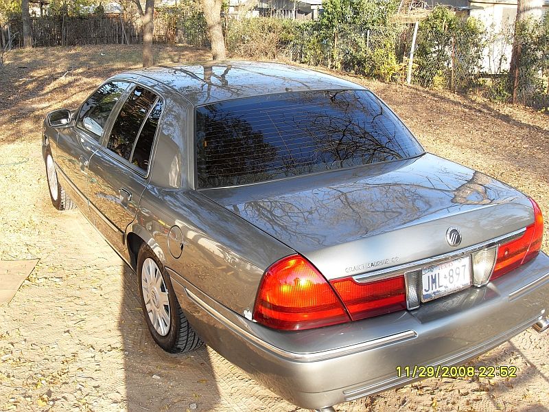 Gray sedan's rear, showing taillights, license plate JML-897, and chrome trim