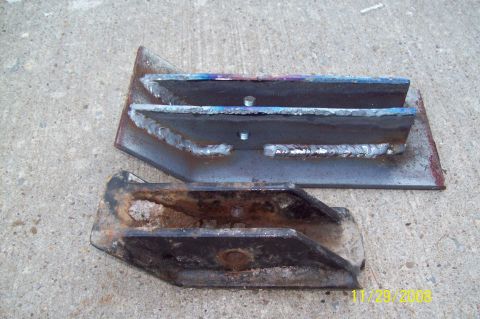 1900 Ford Wagon - Two metal brackets, one showing fresh welds and the other showing significant rust and wear.