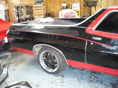 1973 Ford Ranchero - A black and red Ford Ranchero is shown in a workshop with peeling paint and custom wheels.