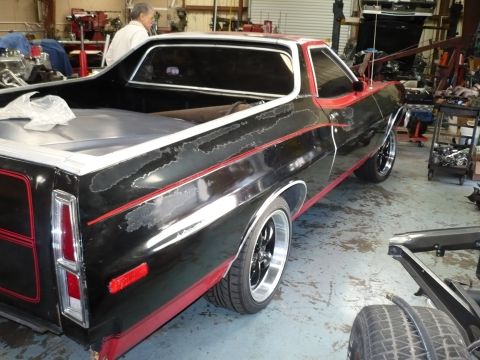 1973 Ford Ranchero - This 1973 Ford Ranchero shows significant paint wear on its black body, contrasted with red trim and accents.