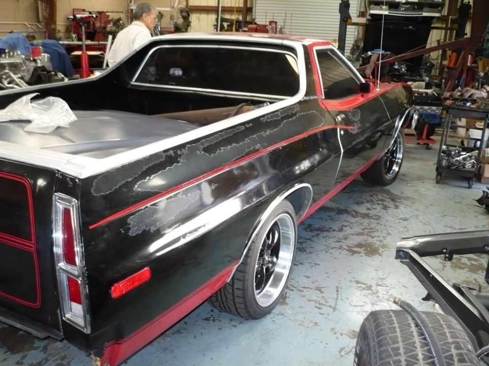 Black and red 1973 Ford Ranchero with peeling paint, seen from the rear quarter