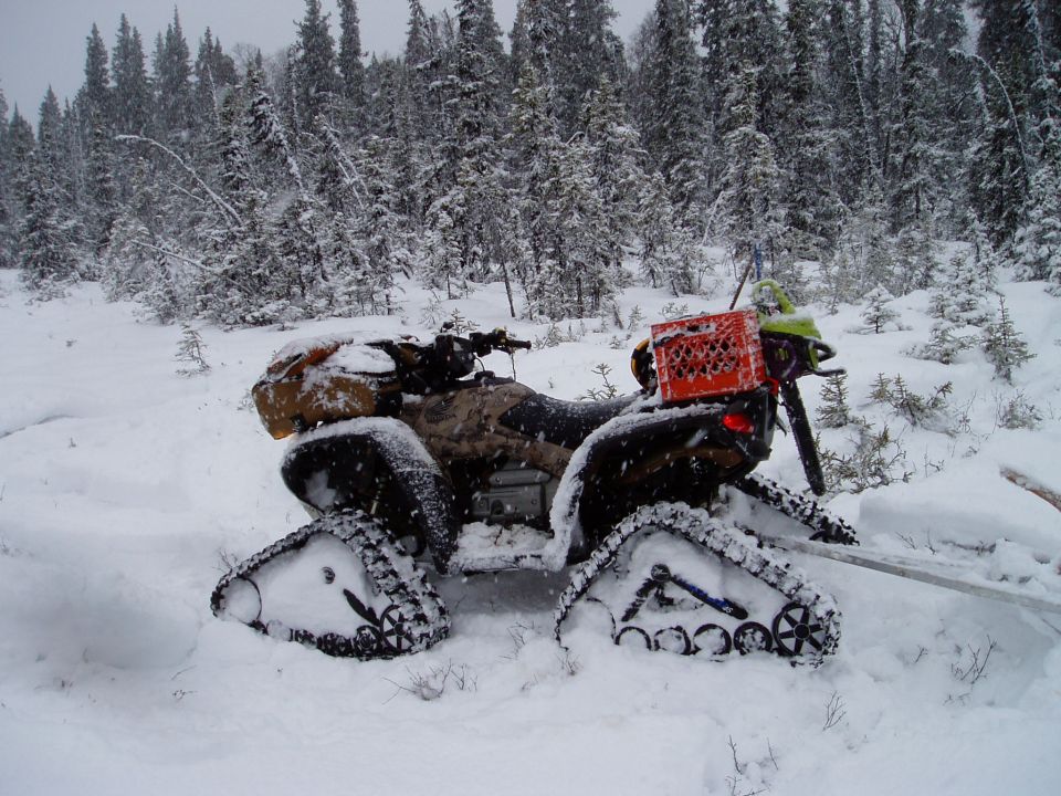 ATV with tracks in snow, orange crate on back