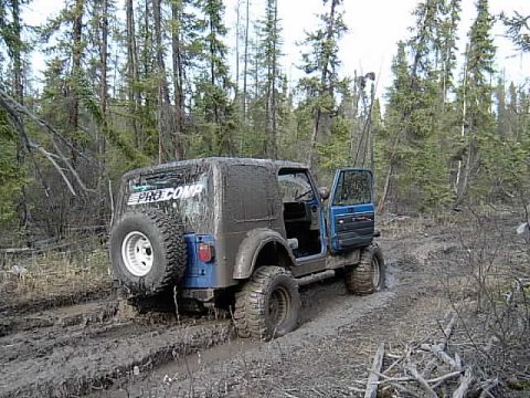 1991 Jeep Wrangler - This Jeep Wrangler is navigating a challenging muddy path in a wooded area.