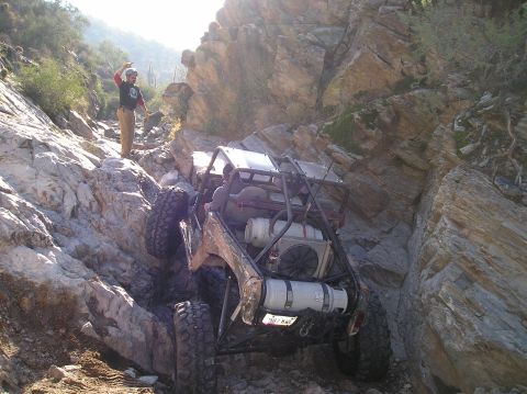 1986 Toyota Hilux - A heavily modified off-road vehicle attempts to traverse a steep, rocky incline in a desert canyon.