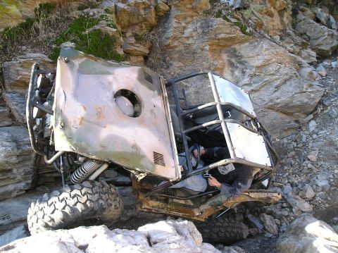 1986 Toyota Hilux - Off-road buggy stuck on rocky terrain, driver attempting to free it.