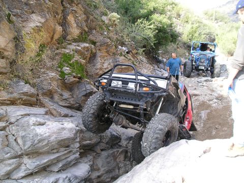 1986 Toyota Hilux - Off-road vehicles tackle a challenging rocky terrain on a trail.