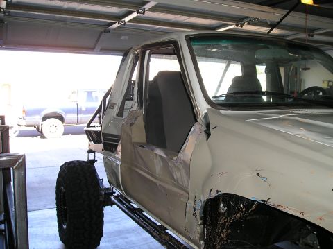 1986 Toyota Hilux - A modified white pickup truck is undergoing repairs or customization inside a garage.