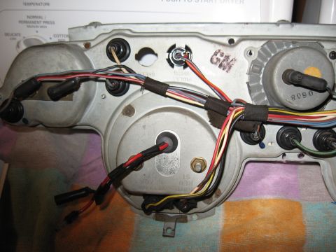 1968 Shelby GT500 - The rear of a vehicle's instrument cluster shows a complex wiring harness and various electrical connections.