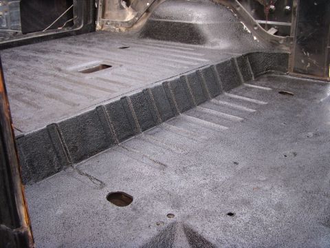 1978 Ford Bronco - Stripped interior of a truck/SUV body shell with the ribbed floor pan, raised rear tub step and wheel-well area freshly sprayed in gray tex…