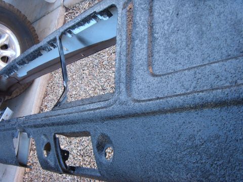 1978 Ford Bronco - A removed sheet-metal body panel lying on gravel, freshly coated in heavily textured black bedliner with pressed contour lines and cut-out…