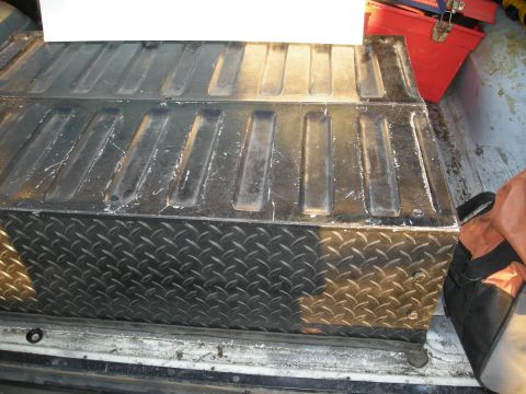 1991 Ford Bronco - Diamond plate toolbox with a ribbed lid, seen inside the bed of a truck.